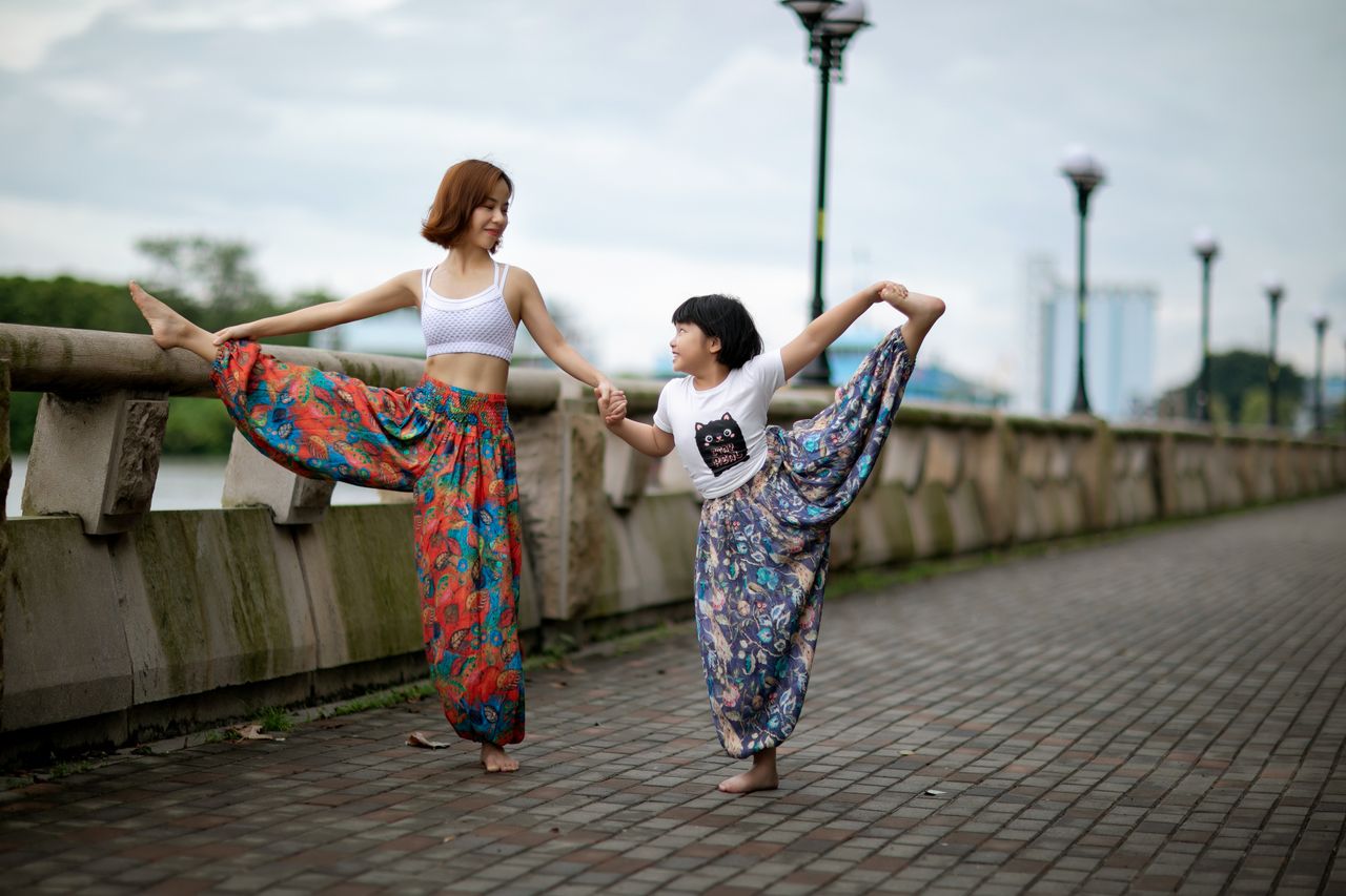 Mother and daughter enjoying yoga outdoors, enhancing flexibility and bonding.